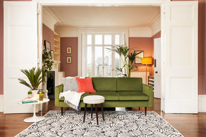 Living room with green sofa and patterned black and white rug in front of window