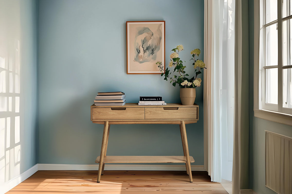 Wooden console table with books and a vase against a blue wall